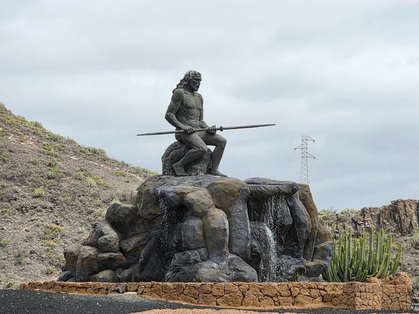 Statua del mencey Guanche Tinerfe seduto con una lancia, su una cascata artificiale.