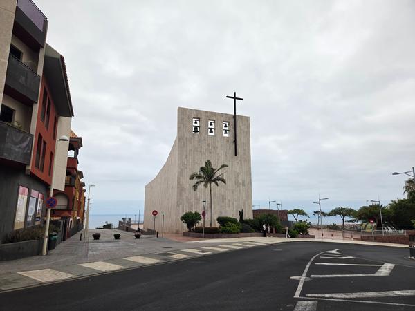 Chiesa moderna con facciata in pietra chiara e croce nera nella zona costiera di Adeje.