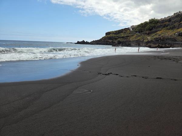 Dettaglio della sabbia vulcanica nera sulla Playa del Bollullo, con l’oceano Atlantico sullo sfondo.