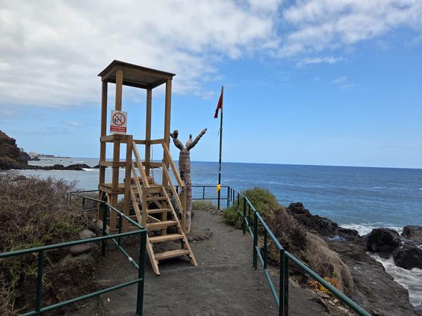 Postazione di salvataggio in legno sulla Playa del Bollullo con bandiera rossa che indica mare agitato.