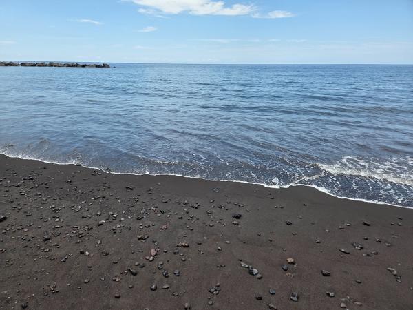 Dettaglio della sabbia nera e dei ciottoli sulla spiaggia vulcanica di Nea