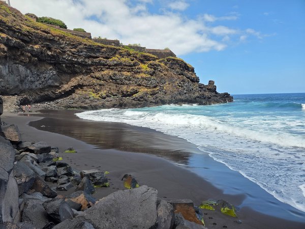 Ampia vista della Playa El Ancón con scogliera vulcanica e sabbia nera, sullo sfondo l’Oceano Atlantico.