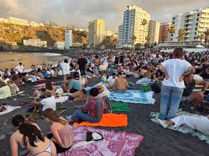 Folla di persone sedute sulla sabbia nera con teli da mare, in attesa del falò e delle attività notturne di San Juan.