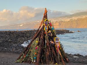 Pira preparata con tronchi di legno, decorazioni floreali e un pupazzo simbolico per il rogo di San Juan.