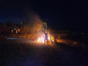 Pupazzo simbolico brucia nel falò acceso sulla spiaggia durante la celebrazione notturna.