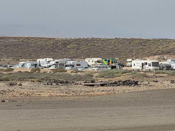 Raggruppamento di camper e furgoni attrezzati parcheggiati nell’area retrostante la spiaggia di La Tejita.